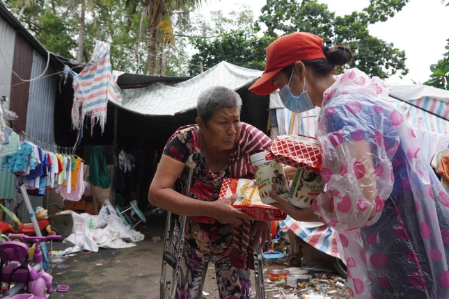 Chị Thảo Nguyên (phải), tác giả bài viết “Nhật ký một tình nguyện viên: Dọn lòng tinh tươm đón nắng mới…” đăng trên báo Giác Ngộ, quay trở lại thêm lần nữa với người dân khu bãi rác khắc khổ. Ảnh: Như Danh/BGN