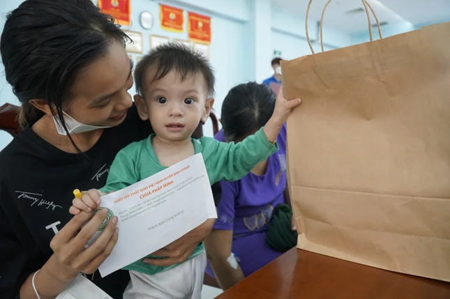 Niềm vui của bé Ngọc, 11 tháng tuổi khi nhận được quà và lì xì. Bé thích thú một tay cầm phong thư, tay còn lại giữ chặt túi quà