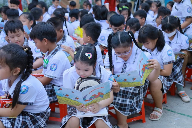 Em đọc sách ngay sân trường khi vừa được các sư tặng