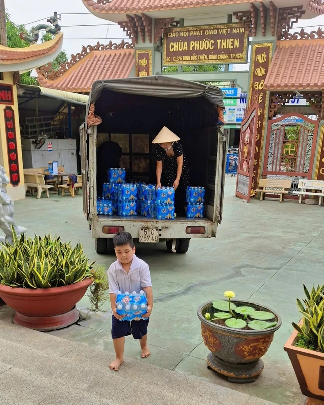 Tình thương không khoảng cách - một em học sinh phụ mẹ vận chuyển nước uống gửi tặng người dân miền Trung - Ảnh: Huệ Quang
