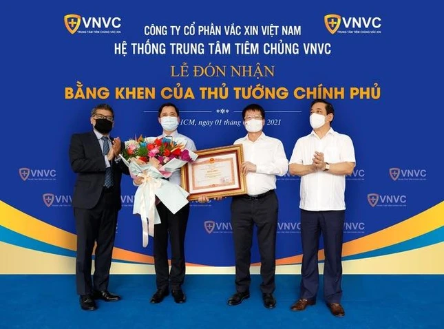 Thứ trưởng Bộ Y tế Trương Quốc Cường (thứ 2 từ phải qua) thay mặt Chính phủ và Bộ Y tế trao tặng bằng khen cho ông Ngô Chí Dũng, Chủ tịch Hội đồng Quản trị kiêm Tổng giám đốc Công ty Cổ phần Vacxin Việt Nam (thứ hai từ trái qua) - Ảnh: Phong Lan.