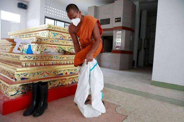 Sư Phra Pongpetch Santijittho mặc PPE để hỏa táng thi thể bệnh nhân Covid-19 tại một tu viện ở ngoại ô Bangkok