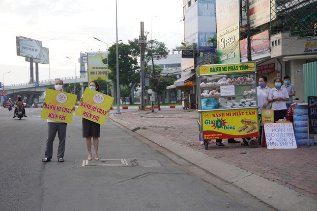 Anh Nguyễn Anh Tuấn cùng bạn cầm bảng "Bánh mì chay miễn phí" chào mời