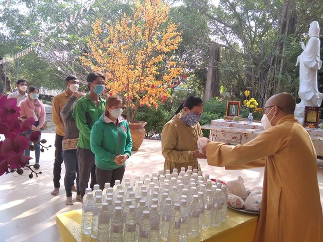 Đại đức Thích Phước Huệ trao nước súc miệng và túi lộc đến người dân