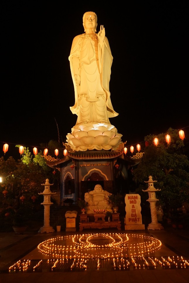 Những ngọn nến được kết thành huy hiệu hoa sen của tổ chức Gia đình Phật tử Việt Nam trước tôn tượng Đức Phật A Di Đà