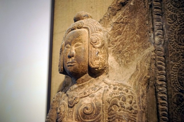 Giữa trán và chóp mũ nổi lên những đường gờ tạo thành hình vòng nối xuống những bông hoa cúc cách điệu hai bên mang tai