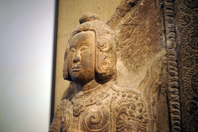 Giữa trán và chóp mũ nổi lên những đường gờ tạo thành hình vòng nối xuống những bông hoa cúc cách điệu hai bên mang tai