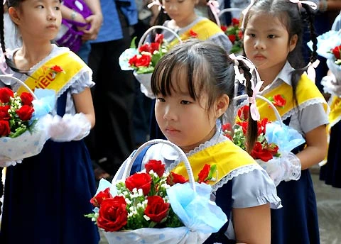 Những em bé xinh xắn dâng những bông hoa hồng đỏ thắm.