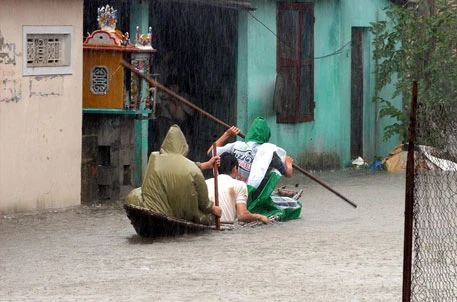 Chèo thuyền trong mưa bão, lũ ở Huế (Ảnh: AFP)