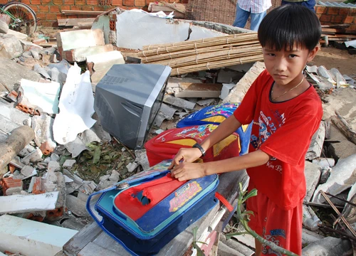 Em Trần Thành, học sinh lớp 4 ở Lý Sơn, thu gom lại sách vở còn sót lại trên nền căn nhà bị sập - Ảnh: Đăng Nam
