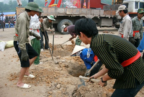 Từ sáng sớm, hàng nghìn người đã đổ về khu đúc tượng cạnh Học viện Phật giáo VN (Sóc Sơn, Hà Nội). Theo lịch âm, hôm nay là ngày "trùng cửu", ngày có ý nghĩa thiêng liêng đặc biệt, rất thích hợp để tiến hành đúc tượng Thánh Gióng - Đức Thánh Phù Đổng Thiên vương. Một mô hình thu nhỏ đặt cạnh khu đúc tượng để phật tử làm lễ, chiêm bái. Khi hoàn thành, tượng cao gần 11 m, độ vươn chéo lên trời khoảng 16 m. Rất nhiều người góp trang sức bằng kim loại quý để hòa cùng dòng đồng nóng chảy lúc đổ vào khuôn. Tại khu đất được cách ly cạnh đó, hai chiếc khuôn của phần đầu ngựa và thân trên Thánh Gióng đang gấp rút được hoàn tất những khâu cuối cùng. Đây là 2 thớt đầu tiên được đúc của tượng đài. Một số chi tiết khác của tượng đài cũng được làm trong mẻ đầu tiên. Hàng trăm thanh đồng đỏ nguyên chất được nung chảy trong lò ga hơn 1.000 độ C. Theo các nghệ nhân, thời gian từ lúc nấu đến lúc đổ đồng mất hơn 2 giờ. Người nghệ nhân cẩn thận trát kín mạch và tạo miệng khuôn để đổ đồng nóng chảy vào. Sau 2 giờ nung, mẻ đồng nóng chảy đổ ra... ...trong khi các nghệ nhân kính cẩn thắp hương mong mọi việc suôn sẻ. Bên ngoài hàng rào, hàng nghìn người chen lấn mong được vào chiêm ngưỡng cận cảnh. Tới dự buổi lễ sáng nay có nguyên Tổng bí thư Đỗ Mười, cùng nhiều vị lãnh đạo. Ngay trước thời khắc 9h9, hòa thượng Thích Thanh Tứ, Phó chủ tịch Trung ương hội Phật giáo VN(người đeo tràng hạt) cùng nhiều quan chức tiến vào khu đúc tượng. Hàng trăm món đồ kim loại quý được thả vào khuôn... ... trước khi dòng đồng đỏ nóng chảy được rót. Theo các nghệ nhân, công đoạn khó nhất của quá trình đúc tượng là khâu làm khuôn: mất 2 tháng. Khuôn phải làm sao để toát lên được thần thái của Thánh Gióng và toàn bộ hoa văn, họa tiết tinh xảo của tượng với đúng tỉ lệ 1:1. Sau khi đổ đầy đồng vào khuôn, cần tới 4 ngày để làm nguội tự nhiên rồi mới phá khuôn.