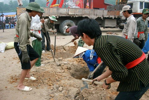 Từ sáng sớm, hàng nghìn người đã đổ về khu đúc tượng cạnh Học viện Phật giáo VN (Sóc Sơn, Hà Nội). Theo lịch âm, hôm nay là ngày "trùng cửu", ngày có ý nghĩa thiêng liêng đặc biệt, rất thích hợp để tiến hành đúc tượng Thánh Gióng - Đức Thánh Phù Đổng Thiên vương. Một mô hình thu nhỏ đặt cạnh khu đúc tượng để phật tử làm lễ, chiêm bái. Khi hoàn thành, tượng cao gần 11 m, độ vươn chéo lên trời khoảng 16 m. Rất nhiều người góp trang sức bằng kim loại quý để hòa cùng dòng đồng nóng chảy lúc đổ vào khuôn. Tại khu đất được cách ly cạnh đó, hai chiếc khuôn của phần đầu ngựa và thân trên Thánh Gióng đang gấp rút được hoàn tất những khâu cuối cùng. Đây là 2 thớt đầu tiên được đúc của tượng đài. Một số chi tiết khác của tượng đài cũng được làm trong mẻ đầu tiên. Hàng trăm thanh đồng đỏ nguyên chất được nung chảy trong lò ga hơn 1.000 độ C. Theo các nghệ nhân, thời gian từ lúc nấu đến lúc đổ đồng mất hơn 2 giờ. Người nghệ nhân cẩn thận trát kín mạch và tạo miệng khuôn để đổ đồng nóng chảy vào. Sau 2 giờ nung, mẻ đồng nóng chảy đổ ra... ...trong khi các nghệ nhân kính cẩn thắp hương mong mọi việc suôn sẻ. Bên ngoài hàng rào, hàng nghìn người chen lấn mong được vào chiêm ngưỡng cận cảnh. Tới dự buổi lễ sáng nay có nguyên Tổng bí thư Đỗ Mười, cùng nhiều vị lãnh đạo. Ngay trước thời khắc 9h9, hòa thượng Thích Thanh Tứ, Phó chủ tịch Trung ương hội Phật giáo VN(người đeo tràng hạt) cùng nhiều quan chức tiến vào khu đúc tượng. Hàng trăm món đồ kim loại quý được thả vào khuôn... ... trước khi dòng đồng đỏ nóng chảy được rót. Theo các nghệ nhân, công đoạn khó nhất của quá trình đúc tượng là khâu làm khuôn: mất 2 tháng. Khuôn phải làm sao để toát lên được thần thái của Thánh Gióng và toàn bộ hoa văn, họa tiết tinh xảo của tượng với đúng tỉ lệ 1:1. Sau khi đổ đầy đồng vào khuôn, cần tới 4 ngày để làm nguội tự nhiên rồi mới phá khuôn.