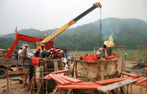 Từ sáng sớm, hàng nghìn người đã đổ về khu đúc tượng cạnh Học viện Phật giáo VN (Sóc Sơn, Hà Nội). Theo lịch âm, hôm nay là ngày "trùng cửu", ngày có ý nghĩa thiêng liêng đặc biệt, rất thích hợp để tiến hành đúc tượng Thánh Gióng - Đức Thánh Phù Đổng Thiên vương. Một mô hình thu nhỏ đặt cạnh khu đúc tượng để phật tử làm lễ, chiêm bái. Khi hoàn thành, tượng cao gần 11 m, độ vươn chéo lên trời khoảng 16 m. Rất nhiều người góp trang sức bằng kim loại quý để hòa cùng dòng đồng nóng chảy lúc đổ vào khuôn. Tại khu đất được cách ly cạnh đó, hai chiếc khuôn của phần đầu ngựa và thân trên Thánh Gióng đang gấp rút được hoàn tất những khâu cuối cùng. Đây là 2 thớt đầu tiên được đúc của tượng đài. Một số chi tiết khác của tượng đài cũng được làm trong mẻ đầu tiên. Hàng trăm thanh đồng đỏ nguyên chất được nung chảy trong lò ga hơn 1.000 độ C. Theo các nghệ nhân, thời gian từ lúc nấu đến lúc đổ đồng mất hơn 2 giờ. Người nghệ nhân cẩn thận trát kín mạch và tạo miệng khuôn để đổ đồng nóng chảy vào. Sau 2 giờ nung, mẻ đồng nóng chảy đổ ra... ...trong khi các nghệ nhân kính cẩn thắp hương mong mọi việc suôn sẻ. Bên ngoài hàng rào, hàng nghìn người chen lấn mong được vào chiêm ngưỡng cận cảnh. Tới dự buổi lễ sáng nay có nguyên Tổng bí thư Đỗ Mười, cùng nhiều vị lãnh đạo. Ngay trước thời khắc 9h9, hòa thượng Thích Thanh Tứ, Phó chủ tịch Trung ương hội Phật giáo VN(người đeo tràng hạt) cùng nhiều quan chức tiến vào khu đúc tượng. Hàng trăm món đồ kim loại quý được thả vào khuôn... ... trước khi dòng đồng đỏ nóng chảy được rót. Theo các nghệ nhân, công đoạn khó nhất của quá trình đúc tượng là khâu làm khuôn: mất 2 tháng. Khuôn phải làm sao để toát lên được thần thái của Thánh Gióng và toàn bộ hoa văn, họa tiết tinh xảo của tượng với đúng tỉ lệ 1:1. Sau khi đổ đầy đồng vào khuôn, cần tới 4 ngày để làm nguội tự nhiên rồi mới phá khuôn.