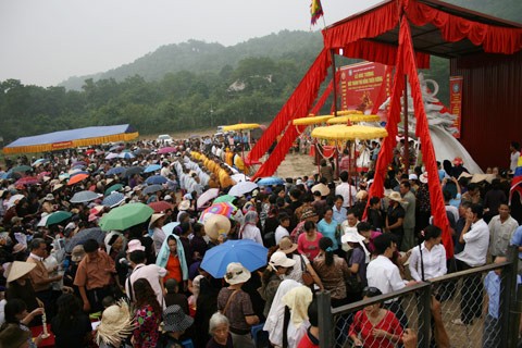 Từ sáng sớm, hàng nghìn người đã đổ về khu đúc tượng cạnh Học viện Phật giáo VN (Sóc Sơn, Hà Nội). Theo lịch âm, hôm nay là ngày "trùng cửu", ngày có ý nghĩa thiêng liêng đặc biệt, rất thích hợp để tiến hành đúc tượng Thánh Gióng - Đức Thánh Phù Đổng Thiên vương. Một mô hình thu nhỏ đặt cạnh khu đúc tượng để phật tử làm lễ, chiêm bái. Khi hoàn thành, tượng cao gần 11 m, độ vươn chéo lên trời khoảng 16 m. Rất nhiều người góp trang sức bằng kim loại quý để hòa cùng dòng đồng nóng chảy lúc đổ vào khuôn. Tại khu đất được cách ly cạnh đó, hai chiếc khuôn của phần đầu ngựa và thân trên Thánh Gióng đang gấp rút được hoàn tất những khâu cuối cùng. Đây là 2 thớt đầu tiên được đúc của tượng đài. Một số chi tiết khác của tượng đài cũng được làm trong mẻ đầu tiên. Hàng trăm thanh đồng đỏ nguyên chất được nung chảy trong lò ga hơn 1.000 độ C. Theo các nghệ nhân, thời gian từ lúc nấu đến lúc đổ đồng mất hơn 2 giờ. Người nghệ nhân cẩn thận trát kín mạch và tạo miệng khuôn để đổ đồng nóng chảy vào. Sau 2 giờ nung, mẻ đồng nóng chảy đổ ra... ...trong khi các nghệ nhân kính cẩn thắp hương mong mọi việc suôn sẻ. Bên ngoài hàng rào, hàng nghìn người chen lấn mong được vào chiêm ngưỡng cận cảnh. Tới dự buổi lễ sáng nay có nguyên Tổng bí thư Đỗ Mười, cùng nhiều vị lãnh đạo. Ngay trước thời khắc 9h9, hòa thượng Thích Thanh Tứ, Phó chủ tịch Trung ương hội Phật giáo VN(người đeo tràng hạt) cùng nhiều quan chức tiến vào khu đúc tượng. Hàng trăm món đồ kim loại quý được thả vào khuôn... ... trước khi dòng đồng đỏ nóng chảy được rót. Theo các nghệ nhân, công đoạn khó nhất của quá trình đúc tượng là khâu làm khuôn: mất 2 tháng. Khuôn phải làm sao để toát lên được thần thái của Thánh Gióng và toàn bộ hoa văn, họa tiết tinh xảo của tượng với đúng tỉ lệ 1:1. Sau khi đổ đầy đồng vào khuôn, cần tới 4 ngày để làm nguội tự nhiên rồi mới phá khuôn.