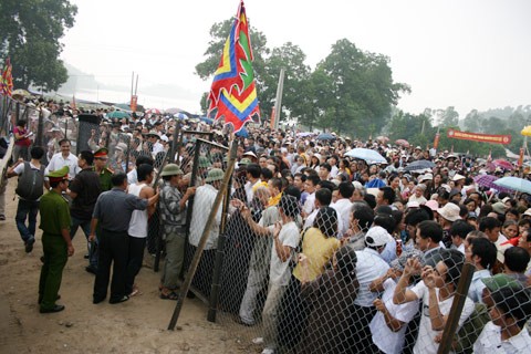 Từ sáng sớm, hàng nghìn người đã đổ về khu đúc tượng cạnh Học viện Phật giáo VN (Sóc Sơn, Hà Nội). Theo lịch âm, hôm nay là ngày "trùng cửu", ngày có ý nghĩa thiêng liêng đặc biệt, rất thích hợp để tiến hành đúc tượng Thánh Gióng - Đức Thánh Phù Đổng Thiên vương. Một mô hình thu nhỏ đặt cạnh khu đúc tượng để phật tử làm lễ, chiêm bái. Khi hoàn thành, tượng cao gần 11 m, độ vươn chéo lên trời khoảng 16 m. Rất nhiều người góp trang sức bằng kim loại quý để hòa cùng dòng đồng nóng chảy lúc đổ vào khuôn. Tại khu đất được cách ly cạnh đó, hai chiếc khuôn của phần đầu ngựa và thân trên Thánh Gióng đang gấp rút được hoàn tất những khâu cuối cùng. Đây là 2 thớt đầu tiên được đúc của tượng đài. Một số chi tiết khác của tượng đài cũng được làm trong mẻ đầu tiên. Hàng trăm thanh đồng đỏ nguyên chất được nung chảy trong lò ga hơn 1.000 độ C. Theo các nghệ nhân, thời gian từ lúc nấu đến lúc đổ đồng mất hơn 2 giờ. Người nghệ nhân cẩn thận trát kín mạch và tạo miệng khuôn để đổ đồng nóng chảy vào. Sau 2 giờ nung, mẻ đồng nóng chảy đổ ra... ...trong khi các nghệ nhân kính cẩn thắp hương mong mọi việc suôn sẻ. Bên ngoài hàng rào, hàng nghìn người chen lấn mong được vào chiêm ngưỡng cận cảnh. Tới dự buổi lễ sáng nay có nguyên Tổng bí thư Đỗ Mười, cùng nhiều vị lãnh đạo. Ngay trước thời khắc 9h9, hòa thượng Thích Thanh Tứ, Phó chủ tịch Trung ương hội Phật giáo VN(người đeo tràng hạt) cùng nhiều quan chức tiến vào khu đúc tượng. Hàng trăm món đồ kim loại quý được thả vào khuôn... ... trước khi dòng đồng đỏ nóng chảy được rót. Theo các nghệ nhân, công đoạn khó nhất của quá trình đúc tượng là khâu làm khuôn: mất 2 tháng. Khuôn phải làm sao để toát lên được thần thái của Thánh Gióng và toàn bộ hoa văn, họa tiết tinh xảo của tượng với đúng tỉ lệ 1:1. Sau khi đổ đầy đồng vào khuôn, cần tới 4 ngày để làm nguội tự nhiên rồi mới phá khuôn.