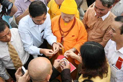 Từ sáng sớm, hàng nghìn người đã đổ về khu đúc tượng cạnh Học viện Phật giáo VN (Sóc Sơn, Hà Nội). Theo lịch âm, hôm nay là ngày "trùng cửu", ngày có ý nghĩa thiêng liêng đặc biệt, rất thích hợp để tiến hành đúc tượng Thánh Gióng - Đức Thánh Phù Đổng Thiên vương. Một mô hình thu nhỏ đặt cạnh khu đúc tượng để phật tử làm lễ, chiêm bái. Khi hoàn thành, tượng cao gần 11 m, độ vươn chéo lên trời khoảng 16 m. Rất nhiều người góp trang sức bằng kim loại quý để hòa cùng dòng đồng nóng chảy lúc đổ vào khuôn. Tại khu đất được cách ly cạnh đó, hai chiếc khuôn của phần đầu ngựa và thân trên Thánh Gióng đang gấp rút được hoàn tất những khâu cuối cùng. Đây là 2 thớt đầu tiên được đúc của tượng đài. Một số chi tiết khác của tượng đài cũng được làm trong mẻ đầu tiên. Hàng trăm thanh đồng đỏ nguyên chất được nung chảy trong lò ga hơn 1.000 độ C. Theo các nghệ nhân, thời gian từ lúc nấu đến lúc đổ đồng mất hơn 2 giờ. Người nghệ nhân cẩn thận trát kín mạch và tạo miệng khuôn để đổ đồng nóng chảy vào. Sau 2 giờ nung, mẻ đồng nóng chảy đổ ra... ...trong khi các nghệ nhân kính cẩn thắp hương mong mọi việc suôn sẻ. Bên ngoài hàng rào, hàng nghìn người chen lấn mong được vào chiêm ngưỡng cận cảnh. Tới dự buổi lễ sáng nay có nguyên Tổng bí thư Đỗ Mười, cùng nhiều vị lãnh đạo. Ngay trước thời khắc 9h9, hòa thượng Thích Thanh Tứ, Phó chủ tịch Trung ương hội Phật giáo VN(người đeo tràng hạt) cùng nhiều quan chức tiến vào khu đúc tượng. Hàng trăm món đồ kim loại quý được thả vào khuôn... ... trước khi dòng đồng đỏ nóng chảy được rót. Theo các nghệ nhân, công đoạn khó nhất của quá trình đúc tượng là khâu làm khuôn: mất 2 tháng. Khuôn phải làm sao để toát lên được thần thái của Thánh Gióng và toàn bộ hoa văn, họa tiết tinh xảo của tượng với đúng tỉ lệ 1:1. Sau khi đổ đầy đồng vào khuôn, cần tới 4 ngày để làm nguội tự nhiên rồi mới phá khuôn.