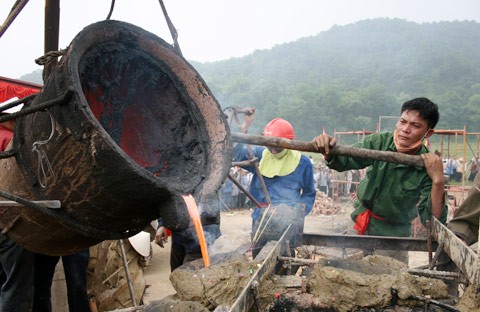 Từ sáng sớm, hàng nghìn người đã đổ về khu đúc tượng cạnh Học viện Phật giáo VN (Sóc Sơn, Hà Nội). Theo lịch âm, hôm nay là ngày "trùng cửu", ngày có ý nghĩa thiêng liêng đặc biệt, rất thích hợp để tiến hành đúc tượng Thánh Gióng - Đức Thánh Phù Đổng Thiên vương. Một mô hình thu nhỏ đặt cạnh khu đúc tượng để phật tử làm lễ, chiêm bái. Khi hoàn thành, tượng cao gần 11 m, độ vươn chéo lên trời khoảng 16 m. Rất nhiều người góp trang sức bằng kim loại quý để hòa cùng dòng đồng nóng chảy lúc đổ vào khuôn. Tại khu đất được cách ly cạnh đó, hai chiếc khuôn của phần đầu ngựa và thân trên Thánh Gióng đang gấp rút được hoàn tất những khâu cuối cùng. Đây là 2 thớt đầu tiên được đúc của tượng đài. Một số chi tiết khác của tượng đài cũng được làm trong mẻ đầu tiên. Hàng trăm thanh đồng đỏ nguyên chất được nung chảy trong lò ga hơn 1.000 độ C. Theo các nghệ nhân, thời gian từ lúc nấu đến lúc đổ đồng mất hơn 2 giờ. Người nghệ nhân cẩn thận trát kín mạch và tạo miệng khuôn để đổ đồng nóng chảy vào. Sau 2 giờ nung, mẻ đồng nóng chảy đổ ra... ...trong khi các nghệ nhân kính cẩn thắp hương mong mọi việc suôn sẻ. Bên ngoài hàng rào, hàng nghìn người chen lấn mong được vào chiêm ngưỡng cận cảnh. Tới dự buổi lễ sáng nay có nguyên Tổng bí thư Đỗ Mười, cùng nhiều vị lãnh đạo. Ngay trước thời khắc 9h9, hòa thượng Thích Thanh Tứ, Phó chủ tịch Trung ương hội Phật giáo VN(người đeo tràng hạt) cùng nhiều quan chức tiến vào khu đúc tượng. Hàng trăm món đồ kim loại quý được thả vào khuôn... ... trước khi dòng đồng đỏ nóng chảy được rót. Theo các nghệ nhân, công đoạn khó nhất của quá trình đúc tượng là khâu làm khuôn: mất 2 tháng. Khuôn phải làm sao để toát lên được thần thái của Thánh Gióng và toàn bộ hoa văn, họa tiết tinh xảo của tượng với đúng tỉ lệ 1:1. Sau khi đổ đầy đồng vào khuôn, cần tới 4 ngày để làm nguội tự nhiên rồi mới phá khuôn.