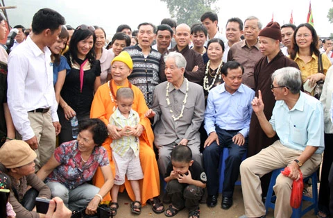 Từ sáng sớm, hàng nghìn người đã đổ về khu đúc tượng cạnh Học viện Phật giáo VN (Sóc Sơn, Hà Nội). Theo lịch âm, hôm nay là ngày "trùng cửu", ngày có ý nghĩa thiêng liêng đặc biệt, rất thích hợp để tiến hành đúc tượng Thánh Gióng - Đức Thánh Phù Đổng Thiên vương. Một mô hình thu nhỏ đặt cạnh khu đúc tượng để phật tử làm lễ, chiêm bái. Khi hoàn thành, tượng cao gần 11 m, độ vươn chéo lên trời khoảng 16 m. Rất nhiều người góp trang sức bằng kim loại quý để hòa cùng dòng đồng nóng chảy lúc đổ vào khuôn. Tại khu đất được cách ly cạnh đó, hai chiếc khuôn của phần đầu ngựa và thân trên Thánh Gióng đang gấp rút được hoàn tất những khâu cuối cùng. Đây là 2 thớt đầu tiên được đúc của tượng đài. Một số chi tiết khác của tượng đài cũng được làm trong mẻ đầu tiên. Hàng trăm thanh đồng đỏ nguyên chất được nung chảy trong lò ga hơn 1.000 độ C. Theo các nghệ nhân, thời gian từ lúc nấu đến lúc đổ đồng mất hơn 2 giờ. Người nghệ nhân cẩn thận trát kín mạch và tạo miệng khuôn để đổ đồng nóng chảy vào. Sau 2 giờ nung, mẻ đồng nóng chảy đổ ra... ...trong khi các nghệ nhân kính cẩn thắp hương mong mọi việc suôn sẻ. Bên ngoài hàng rào, hàng nghìn người chen lấn mong được vào chiêm ngưỡng cận cảnh. Tới dự buổi lễ sáng nay có nguyên Tổng bí thư Đỗ Mười, cùng nhiều vị lãnh đạo. Ngay trước thời khắc 9h9, hòa thượng Thích Thanh Tứ, Phó chủ tịch Trung ương hội Phật giáo VN(người đeo tràng hạt) cùng nhiều quan chức tiến vào khu đúc tượng. Hàng trăm món đồ kim loại quý được thả vào khuôn... ... trước khi dòng đồng đỏ nóng chảy được rót. Theo các nghệ nhân, công đoạn khó nhất của quá trình đúc tượng là khâu làm khuôn: mất 2 tháng. Khuôn phải làm sao để toát lên được thần thái của Thánh Gióng và toàn bộ hoa văn, họa tiết tinh xảo của tượng với đúng tỉ lệ 1:1. Sau khi đổ đầy đồng vào khuôn, cần tới 4 ngày để làm nguội tự nhiên rồi mới phá khuôn.