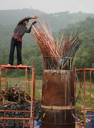 Từ sáng sớm, hàng nghìn người đã đổ về khu đúc tượng cạnh Học viện Phật giáo VN (Sóc Sơn, Hà Nội). Theo lịch âm, hôm nay là ngày "trùng cửu", ngày có ý nghĩa thiêng liêng đặc biệt, rất thích hợp để tiến hành đúc tượng Thánh Gióng - Đức Thánh Phù Đổng Thiên vương. Một mô hình thu nhỏ đặt cạnh khu đúc tượng để phật tử làm lễ, chiêm bái. Khi hoàn thành, tượng cao gần 11 m, độ vươn chéo lên trời khoảng 16 m. Rất nhiều người góp trang sức bằng kim loại quý để hòa cùng dòng đồng nóng chảy lúc đổ vào khuôn. Tại khu đất được cách ly cạnh đó, hai chiếc khuôn của phần đầu ngựa và thân trên Thánh Gióng đang gấp rút được hoàn tất những khâu cuối cùng. Đây là 2 thớt đầu tiên được đúc của tượng đài. Một số chi tiết khác của tượng đài cũng được làm trong mẻ đầu tiên. Hàng trăm thanh đồng đỏ nguyên chất được nung chảy trong lò ga hơn 1.000 độ C. Theo các nghệ nhân, thời gian từ lúc nấu đến lúc đổ đồng mất hơn 2 giờ. Người nghệ nhân cẩn thận trát kín mạch và tạo miệng khuôn để đổ đồng nóng chảy vào. Sau 2 giờ nung, mẻ đồng nóng chảy đổ ra... ...trong khi các nghệ nhân kính cẩn thắp hương mong mọi việc suôn sẻ. Bên ngoài hàng rào, hàng nghìn người chen lấn mong được vào chiêm ngưỡng cận cảnh. Tới dự buổi lễ sáng nay có nguyên Tổng bí thư Đỗ Mười, cùng nhiều vị lãnh đạo. Ngay trước thời khắc 9h9, hòa thượng Thích Thanh Tứ, Phó chủ tịch Trung ương hội Phật giáo VN(người đeo tràng hạt) cùng nhiều quan chức tiến vào khu đúc tượng. Hàng trăm món đồ kim loại quý được thả vào khuôn... ... trước khi dòng đồng đỏ nóng chảy được rót. Theo các nghệ nhân, công đoạn khó nhất của quá trình đúc tượng là khâu làm khuôn: mất 2 tháng. Khuôn phải làm sao để toát lên được thần thái của Thánh Gióng và toàn bộ hoa văn, họa tiết tinh xảo của tượng với đúng tỉ lệ 1:1. Sau khi đổ đầy đồng vào khuôn, cần tới 4 ngày để làm nguội tự nhiên rồi mới phá khuôn.