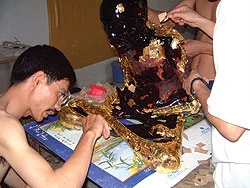 Họa sĩ sơn mài Đào Ngọc Hân đang thếp vàng tượng gốc thiền sư Vũ Khắc Minh