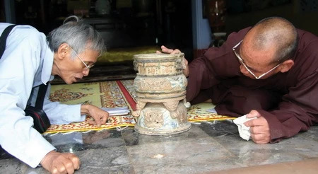 Hòa thượng Thích Lưu Hòa và nhà nghiên cứu Hồ Tấn Phan đang tìm cách đọc những minh văn trên lư trầm