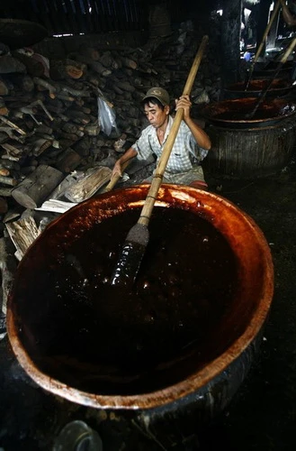 Một công nhân đang làm dodol trên chảo gỗ ở Tangerang, tỉnh Banten (Indonesia) ngày 6-2. Dodol làm bằng gạo nếp, nước dừa và đường là món kẹo đặc biệt bán vào dịp năm mới ở Indonesia. Nhu cầu thị trường tăng khoảng 50% vào dịp đặc biệt này - Ảnh: Reuters