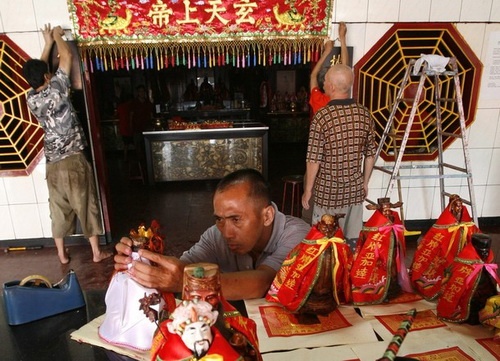 Dọn dẹp, lau rửa đồ đạc và bàn thờ là việc làm vào dịp tết đến. Trong ảnh là một người đàn ông lau các bức tượng thờ trong một ngôi chùa ở Jakarta, Indonesia ngày 7-2 - Ảnh: Reuters