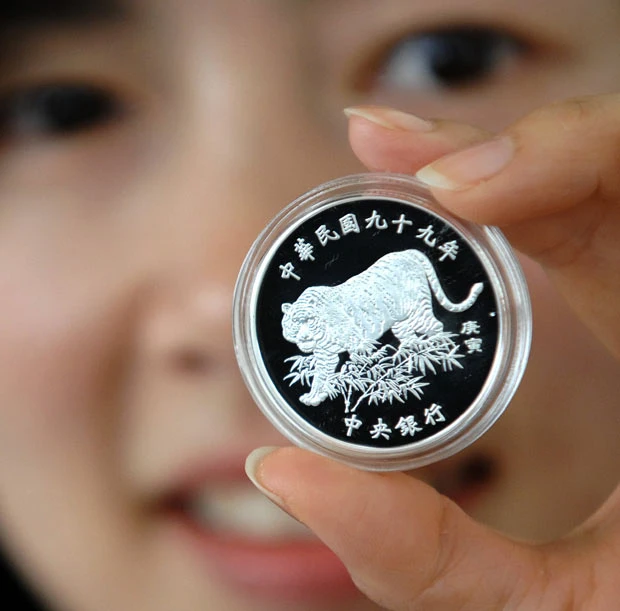 A staff member of Taiwan’s central bank displays a coin issued to mark the year of the tiger