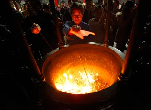 Một người dân Đài Loang đốt đèn và nhang tại đền Xingtian - Ảnh: Reuters