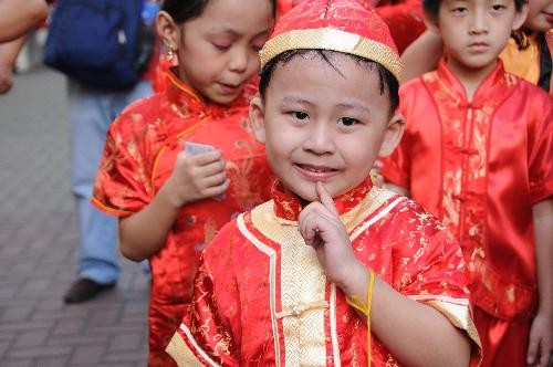 Children in traditional Chinese costumes watch dragon dance held to welcome the Chinese traditional lunar New Year in front of the biggest shopping mall of Philippines in Manila, Feb. 13, 2010.