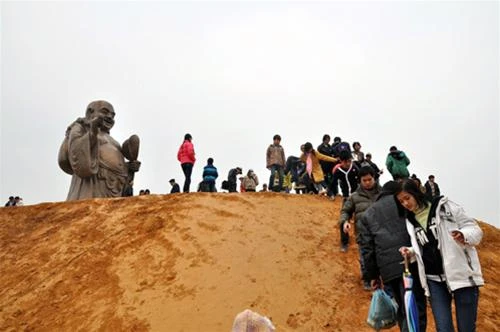 Du khách leo lên quả đồi còn đang xây dựng ngổn ngang để chiêm ngưỡng tượng phật Di Lạc bằng đồng lớn nhất Việt Nam - Ảnh: Thuận Thắng