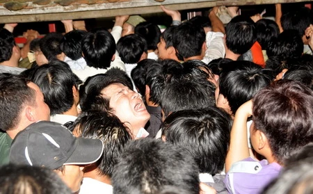 Một người đàn ông gào thét khi bị đám đông xô đẩy trước phủ Cố Trạch (thuộc đền Trần, Nam Định) - một trong ba nơi ban tổ chức đặt bàn phát ấn cho người dân - Ảnh: Thuận Thắng