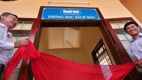 Anh Dương Thành Truyền và ông Võ Xuân Huyện (phải) kéo băng khánh thành phòng đọc sách báo Tuổi Trẻ tại đảo Lý Sơn - Ảnh: Thái Lộc