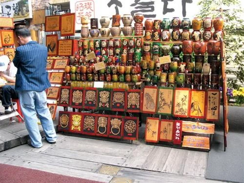 Gian hàng lề đường bán bình gốm và tranh chạm khắc dân gian