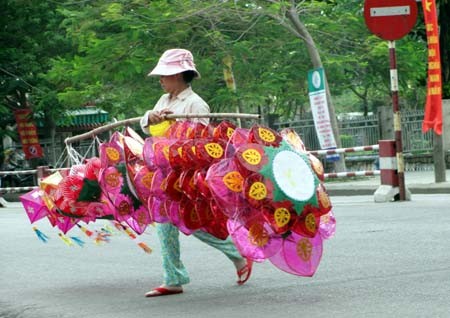 Mỗi khi qua đường, các o dùng tay di chuyển gánh đèn lồng. "Gánh đèn bị tai nạn là chuyện như cơm bữa của xóm đèn lồng chúng tôi rồi", chị Lan tâm sự