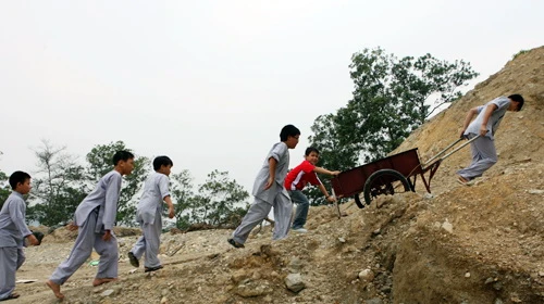 Những cậu bé đang cố đẩy xe kéo đi lấy củi cho bếp ăn của thiền viện