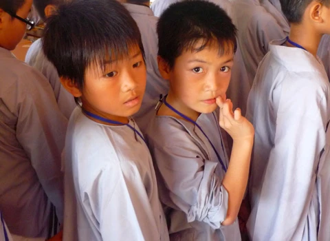 Hơn 600 học sinh tề tựu trong lễ khai giảng. Buổi học thiền đầu tiên. Không giấu nổi sự hồn nhiên. Cùng nhau xuống núi đi khất thực. Cười hồn nhiên trong giờ tiểu thực. Tập trung trở lại khu nhà ở sau giờ ăn trưa. Sư thầy nhẹ nhàng nhắc nhở các em nhỏ đi đúng hàng. Hai em nhỏ tranh thủ giờ nghỉ trưa xem lại bài vở. Các em cùng nhau học Phật pháp. Vốn là nơi tu hành của các bậc chư tăng, song để đáp ứng nhu cầu chúng sinh, Thiền viện Trúc Lâm Tây Thiên đã nhận giúp các "cậu ấm, cô chiêu" tập tu, sửa mình mà không thu bất cứ khoản lệ phí nào. Lớp học năm trước chỉ có 40-50 em nhỏ, do tiếng lành đồn xa, năm nay con số đã gấp hơn 10 lần. Các thầy phải chia làm nhiều khóa học để tiếp nhận các em. Khóa học đầu tiên dành cho các em từ 10 đến 14 tuổi, khai giảng vào ngày 13/6 và sẽ kết thúc sau 2 tuần. Thiền sư Thích Kiến Nguyệt, trụ trì Thiền viện Trúc Lâm Tây Thiên cho biết, do khuôn viên và số lượng thiền sư có hạn nên không thể nhận cùng lúc tất cả em nhỏ. Hiện 90 thầy, cô phải làm việc hết mình để quản lý, dạy dỗ 600 em nhỏ. Nói về lợi ích của việc tu tập, đặc biệt là ngồi thiền, thầy Nguyệt nhận xét: “Thiền là phương pháp tĩnh tâm khai trí. Khoa học đã chứng minh đứa trẻ ngồi thiền thông minh, kiên nhẫn hơn những đứa trẻ không ngồi thiền. Hiện nay, ở nhiều nước đã đưa thiền vào chương trình giáo dục. Các em tranh thủ đọc sách Phật trong giờ nghỉ. Ảnh: Hải Đăng. Ngoài việc học thiền, các sư thầy, sư cô sẽ chỉ dạy cho các em thói quen thức dậy từ 3h sáng, gập chăn màn sao cho vuông vức, ngay ngắn, sau đó nhẹ nhàng di chuyển về giảng đường để tọa thiền. Kết thúc giờ tọa thiền lúc 5h sáng, các em sẽ đến với bữa sáng gọi là tiểu thực. Lũ trẻ tay cầm bát, xếp thành hàng dài ngay ngắn đi về phía Trai đường để tự chọn khẩu phần ăn chay cho mình. 7h30 là bắt đầu giờ học đạo. Các em nhỏ được dạy kinh Phật để biết nhìn vạn vật bằng tình yêu thương, biết đúng, biết sai để sớm "phát tâm tỉnh giác, xa lìa chỗ tối tăm". 11h trưa là đến giờ khất thực (ăn trưa). Trước khi ăn, lũ trẻ phải chắp tay cầu nguyện và cùng nghe thầy giảng về nguồn gốc hạt lúa, củ khoai, ý nghĩa của những bữa ăn chay... Buổi chiều những cậu ấm, cô chiêu vốn quen với nếp sống thị thành, quen với sự nuông chiều, ỉ lại vào cha mẹ, người thân, được dạy cách làm việc nhà như: nấu cơm bằng bếp củi, rửa bát, nhặt rau... Các em kết thúc một ngày bằng lễ sám hối tại chánh điện, tức là xem xét lại tất cả những hành động trong ngày để nhận biết đúng, sai và sửa mình. Có nhiều lý do để các bậc phụ huynh đưa con em đến tập tu. Người thì muốn con tách khỏi cuộc sống thường nhật để cai games, người muốn con được học Phật pháp để chúng hiểu rõ hơn về ý nghĩa cuộc sống, trân trọng những gì đang có, để chúng biết được nguồn gốc của hạt lúa, củ khoai, biết trân trọng thành quả lao động của người khác. Và cũng có những ông bố bà mẹ đưa con lên chỉ để con biết thế nào là nhặt rau, quét nhà, nấu cơm… Chia sẻ cảm giác về ngày đầu tập tu, cô bé Phạm Phương Thảo, 14 tuổi, thật thà: “Cháu chẳng muốn lên đây, ở đây chán lắm, chẳng qua là bố mẹ ép. Cháu nghiện Audition nặng, chỉ cần hai chai nước, chẳng cần ăn gì, cháu có thể ngồi cả ngày. Giờ này bọn bạn cháu chắc đang ngồi ở quán net đầu đường Tô Hiệu (Cầu Giấy, Hà Nội)". Khác với sự bạo dạn của Thảo, hai chị em Nguyễn Việt Hà (14 tuổi) và Nguyễn Việt Hương (6 tuổi) ở Đống Đa (Hà Nội) tỏ ra dè dặt khi tiếp xúc với người lạ. Hương nhỏ tuổi nhất tại khóa học lần này. Thấy bố mẹ đưa chị lên đây để có thời gian nghỉ ngơi sau một năm học vất vả, cô bé nhất định đòi lên cùng chị. Đôi mắt sưng húp, Hà nói: “Hết giờ sám hối chiều qua, em cháu bắt đầu khóc đòi mẹ. Các cô dỗ mãi nó mới chịu nín. 11h đêm nó lại khóc, thế là cả phòng cháu khóc theo. Cháu nhớ nhà lắm. Cho cháu mượn điện thoại để gọi về cho mẹ được không?”. Được mượn điện thoại, cô bé vừa bấm số gọi cho mẹ vừa nước mắt lưng tròng. Cô chị ôm lấy cô em, thút thít nói chuyện với mẹ… Một em trai cũng không cầm được nước mắt vì nhớ nhà. Ảnh: Hải Đăng. Phía ngoài bậc thang bước lên giảng đường, hai ni cô cũng ra sức dỗ dành cậu bé Bùi Công Huy (10 tuổi) ở Hà Giang đang đòi về. Huy vừa khóc vừa nói: “Cháu không quen ăn chay, nhạt lắm. Ở đây cháu còn phải tự gập quần áo, nấu cơm, rửa bát, đến giờ ăn còn phải tự bưng bát, xếp hàng xới cơm… Cháu không quen, cháu muốn về với mẹ”. Các em lớn thì tỏ ra cứng rắn và thích nghi nhanh hơn với nếp sống tại thiền viện. Khuôn mặt tuấn tú, đeo kính cận, cậu bé Phan Thành Hưng (16 tuổi) ở phường Bách Khoa, Hà Nội, nhẹ nhàng lật giở quyển kinh. “Đây là lần thứ hai em lên thiền viện. Năm ngoái vì quá nghiện Internet nên bố mẹ đưa em lên. Năm nay, nghỉ hè là em xin bố mẹ lên luôn. Bây giờ em đã quen với việc ăn chay, dậy sớm từ 3h sáng, tự xúc khẩu phần ăn cho mình, tự rửa bát, quét nhà. Các thầy, các cô chỉ bảo ân cần lắm”, Hưng chia sẻ. Bóng chiều buông xuống, anh Quách Ngọc Huy (Tây Hồ, Hà Nội) đang chuẩn bị chia tay hai cô con gái để về Hà Nội. "Tôi có 3 con gái và muốn cả ba cháu lên đây nhưng vì cháu út mới 4 tuổi nên đành phải ở nhà với mẹ. Thú thật lên đây tôi thấy không khí thật thanh bình. Nhìn thấy con tự rửa bát, quét nhà mà tôi mừng quá. Ở nhà chúng có biết làm gì đâu. Tôi mong nhà chùa mở thêm nhiều khóa học như thế này để các em có được một học kỳ 3 thật hữu ích", anh Huy nói. 18h30 chiều, mặt trời đỏ lự phía sau mái chùa cong cong. Hàng thông reo vi vu. Phía nhà dân dưới chân núi, mấy cột khói bếp mịt mùng hòa vào khói lam chiều. Trên giảng đường ở thiền viện, đám trẻ nghiêm trang chắp tay trước tượng Phật và cầu nguyện theo các thầy để chúng sinh “xa rời đường dữ”, được ấm no, hạnh phúc.