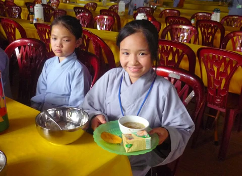 Hơn 600 học sinh tề tựu trong lễ khai giảng. Buổi học thiền đầu tiên. Không giấu nổi sự hồn nhiên. Cùng nhau xuống núi đi khất thực. Cười hồn nhiên trong giờ tiểu thực. Tập trung trở lại khu nhà ở sau giờ ăn trưa. Sư thầy nhẹ nhàng nhắc nhở các em nhỏ đi đúng hàng. Hai em nhỏ tranh thủ giờ nghỉ trưa xem lại bài vở. Các em cùng nhau học Phật pháp. Vốn là nơi tu hành của các bậc chư tăng, song để đáp ứng nhu cầu chúng sinh, Thiền viện Trúc Lâm Tây Thiên đã nhận giúp các "cậu ấm, cô chiêu" tập tu, sửa mình mà không thu bất cứ khoản lệ phí nào. Lớp học năm trước chỉ có 40-50 em nhỏ, do tiếng lành đồn xa, năm nay con số đã gấp hơn 10 lần. Các thầy phải chia làm nhiều khóa học để tiếp nhận các em. Khóa học đầu tiên dành cho các em từ 10 đến 14 tuổi, khai giảng vào ngày 13/6 và sẽ kết thúc sau 2 tuần. Thiền sư Thích Kiến Nguyệt, trụ trì Thiền viện Trúc Lâm Tây Thiên cho biết, do khuôn viên và số lượng thiền sư có hạn nên không thể nhận cùng lúc tất cả em nhỏ. Hiện 90 thầy, cô phải làm việc hết mình để quản lý, dạy dỗ 600 em nhỏ. Nói về lợi ích của việc tu tập, đặc biệt là ngồi thiền, thầy Nguyệt nhận xét: “Thiền là phương pháp tĩnh tâm khai trí. Khoa học đã chứng minh đứa trẻ ngồi thiền thông minh, kiên nhẫn hơn những đứa trẻ không ngồi thiền. Hiện nay, ở nhiều nước đã đưa thiền vào chương trình giáo dục. Các em tranh thủ đọc sách Phật trong giờ nghỉ. Ảnh: Hải Đăng. Ngoài việc học thiền, các sư thầy, sư cô sẽ chỉ dạy cho các em thói quen thức dậy từ 3h sáng, gập chăn màn sao cho vuông vức, ngay ngắn, sau đó nhẹ nhàng di chuyển về giảng đường để tọa thiền. Kết thúc giờ tọa thiền lúc 5h sáng, các em sẽ đến với bữa sáng gọi là tiểu thực. Lũ trẻ tay cầm bát, xếp thành hàng dài ngay ngắn đi về phía Trai đường để tự chọn khẩu phần ăn chay cho mình. 7h30 là bắt đầu giờ học đạo. Các em nhỏ được dạy kinh Phật để biết nhìn vạn vật bằng tình yêu thương, biết đúng, biết sai để sớm "phát tâm tỉnh giác, xa lìa chỗ tối tăm". 11h trưa là đến giờ khất thực (ăn trưa). Trước khi ăn, lũ trẻ phải chắp tay cầu nguyện và cùng nghe thầy giảng về nguồn gốc hạt lúa, củ khoai, ý nghĩa của những bữa ăn chay... Buổi chiều những cậu ấm, cô chiêu vốn quen với nếp sống thị thành, quen với sự nuông chiều, ỉ lại vào cha mẹ, người thân, được dạy cách làm việc nhà như: nấu cơm bằng bếp củi, rửa bát, nhặt rau... Các em kết thúc một ngày bằng lễ sám hối tại chánh điện, tức là xem xét lại tất cả những hành động trong ngày để nhận biết đúng, sai và sửa mình. Có nhiều lý do để các bậc phụ huynh đưa con em đến tập tu. Người thì muốn con tách khỏi cuộc sống thường nhật để cai games, người muốn con được học Phật pháp để chúng hiểu rõ hơn về ý nghĩa cuộc sống, trân trọng những gì đang có, để chúng biết được nguồn gốc của hạt lúa, củ khoai, biết trân trọng thành quả lao động của người khác. Và cũng có những ông bố bà mẹ đưa con lên chỉ để con biết thế nào là nhặt rau, quét nhà, nấu cơm… Chia sẻ cảm giác về ngày đầu tập tu, cô bé Phạm Phương Thảo, 14 tuổi, thật thà: “Cháu chẳng muốn lên đây, ở đây chán lắm, chẳng qua là bố mẹ ép. Cháu nghiện Audition nặng, chỉ cần hai chai nước, chẳng cần ăn gì, cháu có thể ngồi cả ngày. Giờ này bọn bạn cháu chắc đang ngồi ở quán net đầu đường Tô Hiệu (Cầu Giấy, Hà Nội)". Khác với sự bạo dạn của Thảo, hai chị em Nguyễn Việt Hà (14 tuổi) và Nguyễn Việt Hương (6 tuổi) ở Đống Đa (Hà Nội) tỏ ra dè dặt khi tiếp xúc với người lạ. Hương nhỏ tuổi nhất tại khóa học lần này. Thấy bố mẹ đưa chị lên đây để có thời gian nghỉ ngơi sau một năm học vất vả, cô bé nhất định đòi lên cùng chị. Đôi mắt sưng húp, Hà nói: “Hết giờ sám hối chiều qua, em cháu bắt đầu khóc đòi mẹ. Các cô dỗ mãi nó mới chịu nín. 11h đêm nó lại khóc, thế là cả phòng cháu khóc theo. Cháu nhớ nhà lắm. Cho cháu mượn điện thoại để gọi về cho mẹ được không?”. Được mượn điện thoại, cô bé vừa bấm số gọi cho mẹ vừa nước mắt lưng tròng. Cô chị ôm lấy cô em, thút thít nói chuyện với mẹ… Một em trai cũng không cầm được nước mắt vì nhớ nhà. Ảnh: Hải Đăng. Phía ngoài bậc thang bước lên giảng đường, hai ni cô cũng ra sức dỗ dành cậu bé Bùi Công Huy (10 tuổi) ở Hà Giang đang đòi về. Huy vừa khóc vừa nói: “Cháu không quen ăn chay, nhạt lắm. Ở đây cháu còn phải tự gập quần áo, nấu cơm, rửa bát, đến giờ ăn còn phải tự bưng bát, xếp hàng xới cơm… Cháu không quen, cháu muốn về với mẹ”. Các em lớn thì tỏ ra cứng rắn và thích nghi nhanh hơn với nếp sống tại thiền viện. Khuôn mặt tuấn tú, đeo kính cận, cậu bé Phan Thành Hưng (16 tuổi) ở phường Bách Khoa, Hà Nội, nhẹ nhàng lật giở quyển kinh. “Đây là lần thứ hai em lên thiền viện. Năm ngoái vì quá nghiện Internet nên bố mẹ đưa em lên. Năm nay, nghỉ hè là em xin bố mẹ lên luôn. Bây giờ em đã quen với việc ăn chay, dậy sớm từ 3h sáng, tự xúc khẩu phần ăn cho mình, tự rửa bát, quét nhà. Các thầy, các cô chỉ bảo ân cần lắm”, Hưng chia sẻ. Bóng chiều buông xuống, anh Quách Ngọc Huy (Tây Hồ, Hà Nội) đang chuẩn bị chia tay hai cô con gái để về Hà Nội. "Tôi có 3 con gái và muốn cả ba cháu lên đây nhưng vì cháu út mới 4 tuổi nên đành phải ở nhà với mẹ. Thú thật lên đây tôi thấy không khí thật thanh bình. Nhìn thấy con tự rửa bát, quét nhà mà tôi mừng quá. Ở nhà chúng có biết làm gì đâu. Tôi mong nhà chùa mở thêm nhiều khóa học như thế này để các em có được một học kỳ 3 thật hữu ích", anh Huy nói. 18h30 chiều, mặt trời đỏ lự phía sau mái chùa cong cong. Hàng thông reo vi vu. Phía nhà dân dưới chân núi, mấy cột khói bếp mịt mùng hòa vào khói lam chiều. Trên giảng đường ở thiền viện, đám trẻ nghiêm trang chắp tay trước tượng Phật và cầu nguyện theo các thầy để chúng sinh “xa rời đường dữ”, được ấm no, hạnh phúc.