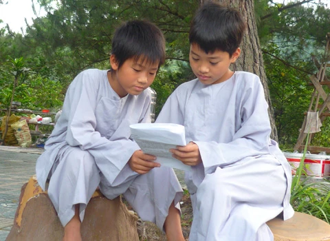 Hơn 600 học sinh tề tựu trong lễ khai giảng. Buổi học thiền đầu tiên. Không giấu nổi sự hồn nhiên. Cùng nhau xuống núi đi khất thực. Cười hồn nhiên trong giờ tiểu thực. Tập trung trở lại khu nhà ở sau giờ ăn trưa. Sư thầy nhẹ nhàng nhắc nhở các em nhỏ đi đúng hàng. Hai em nhỏ tranh thủ giờ nghỉ trưa xem lại bài vở. Các em cùng nhau học Phật pháp. Vốn là nơi tu hành của các bậc chư tăng, song để đáp ứng nhu cầu chúng sinh, Thiền viện Trúc Lâm Tây Thiên đã nhận giúp các "cậu ấm, cô chiêu" tập tu, sửa mình mà không thu bất cứ khoản lệ phí nào. Lớp học năm trước chỉ có 40-50 em nhỏ, do tiếng lành đồn xa, năm nay con số đã gấp hơn 10 lần. Các thầy phải chia làm nhiều khóa học để tiếp nhận các em. Khóa học đầu tiên dành cho các em từ 10 đến 14 tuổi, khai giảng vào ngày 13/6 và sẽ kết thúc sau 2 tuần. Thiền sư Thích Kiến Nguyệt, trụ trì Thiền viện Trúc Lâm Tây Thiên cho biết, do khuôn viên và số lượng thiền sư có hạn nên không thể nhận cùng lúc tất cả em nhỏ. Hiện 90 thầy, cô phải làm việc hết mình để quản lý, dạy dỗ 600 em nhỏ. Nói về lợi ích của việc tu tập, đặc biệt là ngồi thiền, thầy Nguyệt nhận xét: “Thiền là phương pháp tĩnh tâm khai trí. Khoa học đã chứng minh đứa trẻ ngồi thiền thông minh, kiên nhẫn hơn những đứa trẻ không ngồi thiền. Hiện nay, ở nhiều nước đã đưa thiền vào chương trình giáo dục. Các em tranh thủ đọc sách Phật trong giờ nghỉ. Ảnh: Hải Đăng. Ngoài việc học thiền, các sư thầy, sư cô sẽ chỉ dạy cho các em thói quen thức dậy từ 3h sáng, gập chăn màn sao cho vuông vức, ngay ngắn, sau đó nhẹ nhàng di chuyển về giảng đường để tọa thiền. Kết thúc giờ tọa thiền lúc 5h sáng, các em sẽ đến với bữa sáng gọi là tiểu thực. Lũ trẻ tay cầm bát, xếp thành hàng dài ngay ngắn đi về phía Trai đường để tự chọn khẩu phần ăn chay cho mình. 7h30 là bắt đầu giờ học đạo. Các em nhỏ được dạy kinh Phật để biết nhìn vạn vật bằng tình yêu thương, biết đúng, biết sai để sớm "phát tâm tỉnh giác, xa lìa chỗ tối tăm". 11h trưa là đến giờ khất thực (ăn trưa). Trước khi ăn, lũ trẻ phải chắp tay cầu nguyện và cùng nghe thầy giảng về nguồn gốc hạt lúa, củ khoai, ý nghĩa của những bữa ăn chay... Buổi chiều những cậu ấm, cô chiêu vốn quen với nếp sống thị thành, quen với sự nuông chiều, ỉ lại vào cha mẹ, người thân, được dạy cách làm việc nhà như: nấu cơm bằng bếp củi, rửa bát, nhặt rau... Các em kết thúc một ngày bằng lễ sám hối tại chánh điện, tức là xem xét lại tất cả những hành động trong ngày để nhận biết đúng, sai và sửa mình. Có nhiều lý do để các bậc phụ huynh đưa con em đến tập tu. Người thì muốn con tách khỏi cuộc sống thường nhật để cai games, người muốn con được học Phật pháp để chúng hiểu rõ hơn về ý nghĩa cuộc sống, trân trọng những gì đang có, để chúng biết được nguồn gốc của hạt lúa, củ khoai, biết trân trọng thành quả lao động của người khác. Và cũng có những ông bố bà mẹ đưa con lên chỉ để con biết thế nào là nhặt rau, quét nhà, nấu cơm… Chia sẻ cảm giác về ngày đầu tập tu, cô bé Phạm Phương Thảo, 14 tuổi, thật thà: “Cháu chẳng muốn lên đây, ở đây chán lắm, chẳng qua là bố mẹ ép. Cháu nghiện Audition nặng, chỉ cần hai chai nước, chẳng cần ăn gì, cháu có thể ngồi cả ngày. Giờ này bọn bạn cháu chắc đang ngồi ở quán net đầu đường Tô Hiệu (Cầu Giấy, Hà Nội)". Khác với sự bạo dạn của Thảo, hai chị em Nguyễn Việt Hà (14 tuổi) và Nguyễn Việt Hương (6 tuổi) ở Đống Đa (Hà Nội) tỏ ra dè dặt khi tiếp xúc với người lạ. Hương nhỏ tuổi nhất tại khóa học lần này. Thấy bố mẹ đưa chị lên đây để có thời gian nghỉ ngơi sau một năm học vất vả, cô bé nhất định đòi lên cùng chị. Đôi mắt sưng húp, Hà nói: “Hết giờ sám hối chiều qua, em cháu bắt đầu khóc đòi mẹ. Các cô dỗ mãi nó mới chịu nín. 11h đêm nó lại khóc, thế là cả phòng cháu khóc theo. Cháu nhớ nhà lắm. Cho cháu mượn điện thoại để gọi về cho mẹ được không?”. Được mượn điện thoại, cô bé vừa bấm số gọi cho mẹ vừa nước mắt lưng tròng. Cô chị ôm lấy cô em, thút thít nói chuyện với mẹ… Một em trai cũng không cầm được nước mắt vì nhớ nhà. Ảnh: Hải Đăng. Phía ngoài bậc thang bước lên giảng đường, hai ni cô cũng ra sức dỗ dành cậu bé Bùi Công Huy (10 tuổi) ở Hà Giang đang đòi về. Huy vừa khóc vừa nói: “Cháu không quen ăn chay, nhạt lắm. Ở đây cháu còn phải tự gập quần áo, nấu cơm, rửa bát, đến giờ ăn còn phải tự bưng bát, xếp hàng xới cơm… Cháu không quen, cháu muốn về với mẹ”. Các em lớn thì tỏ ra cứng rắn và thích nghi nhanh hơn với nếp sống tại thiền viện. Khuôn mặt tuấn tú, đeo kính cận, cậu bé Phan Thành Hưng (16 tuổi) ở phường Bách Khoa, Hà Nội, nhẹ nhàng lật giở quyển kinh. “Đây là lần thứ hai em lên thiền viện. Năm ngoái vì quá nghiện Internet nên bố mẹ đưa em lên. Năm nay, nghỉ hè là em xin bố mẹ lên luôn. Bây giờ em đã quen với việc ăn chay, dậy sớm từ 3h sáng, tự xúc khẩu phần ăn cho mình, tự rửa bát, quét nhà. Các thầy, các cô chỉ bảo ân cần lắm”, Hưng chia sẻ. Bóng chiều buông xuống, anh Quách Ngọc Huy (Tây Hồ, Hà Nội) đang chuẩn bị chia tay hai cô con gái để về Hà Nội. "Tôi có 3 con gái và muốn cả ba cháu lên đây nhưng vì cháu út mới 4 tuổi nên đành phải ở nhà với mẹ. Thú thật lên đây tôi thấy không khí thật thanh bình. Nhìn thấy con tự rửa bát, quét nhà mà tôi mừng quá. Ở nhà chúng có biết làm gì đâu. Tôi mong nhà chùa mở thêm nhiều khóa học như thế này để các em có được một học kỳ 3 thật hữu ích", anh Huy nói. 18h30 chiều, mặt trời đỏ lự phía sau mái chùa cong cong. Hàng thông reo vi vu. Phía nhà dân dưới chân núi, mấy cột khói bếp mịt mùng hòa vào khói lam chiều. Trên giảng đường ở thiền viện, đám trẻ nghiêm trang chắp tay trước tượng Phật và cầu nguyện theo các thầy để chúng sinh “xa rời đường dữ”, được ấm no, hạnh phúc.