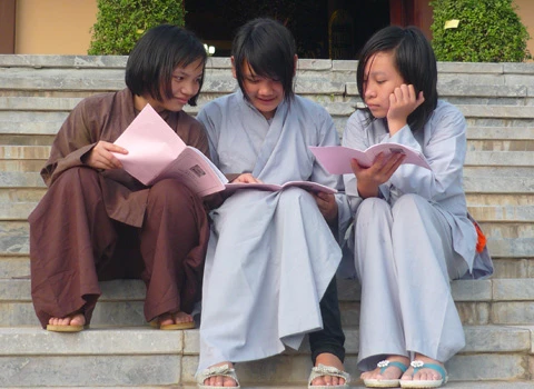 Hơn 600 học sinh tề tựu trong lễ khai giảng. Buổi học thiền đầu tiên. Không giấu nổi sự hồn nhiên. Cùng nhau xuống núi đi khất thực. Cười hồn nhiên trong giờ tiểu thực. Tập trung trở lại khu nhà ở sau giờ ăn trưa. Sư thầy nhẹ nhàng nhắc nhở các em nhỏ đi đúng hàng. Hai em nhỏ tranh thủ giờ nghỉ trưa xem lại bài vở. Các em cùng nhau học Phật pháp. Vốn là nơi tu hành của các bậc chư tăng, song để đáp ứng nhu cầu chúng sinh, Thiền viện Trúc Lâm Tây Thiên đã nhận giúp các "cậu ấm, cô chiêu" tập tu, sửa mình mà không thu bất cứ khoản lệ phí nào. Lớp học năm trước chỉ có 40-50 em nhỏ, do tiếng lành đồn xa, năm nay con số đã gấp hơn 10 lần. Các thầy phải chia làm nhiều khóa học để tiếp nhận các em. Khóa học đầu tiên dành cho các em từ 10 đến 14 tuổi, khai giảng vào ngày 13/6 và sẽ kết thúc sau 2 tuần. Thiền sư Thích Kiến Nguyệt, trụ trì Thiền viện Trúc Lâm Tây Thiên cho biết, do khuôn viên và số lượng thiền sư có hạn nên không thể nhận cùng lúc tất cả em nhỏ. Hiện 90 thầy, cô phải làm việc hết mình để quản lý, dạy dỗ 600 em nhỏ. Nói về lợi ích của việc tu tập, đặc biệt là ngồi thiền, thầy Nguyệt nhận xét: “Thiền là phương pháp tĩnh tâm khai trí. Khoa học đã chứng minh đứa trẻ ngồi thiền thông minh, kiên nhẫn hơn những đứa trẻ không ngồi thiền. Hiện nay, ở nhiều nước đã đưa thiền vào chương trình giáo dục. Các em tranh thủ đọc sách Phật trong giờ nghỉ. Ảnh: Hải Đăng. Ngoài việc học thiền, các sư thầy, sư cô sẽ chỉ dạy cho các em thói quen thức dậy từ 3h sáng, gập chăn màn sao cho vuông vức, ngay ngắn, sau đó nhẹ nhàng di chuyển về giảng đường để tọa thiền. Kết thúc giờ tọa thiền lúc 5h sáng, các em sẽ đến với bữa sáng gọi là tiểu thực. Lũ trẻ tay cầm bát, xếp thành hàng dài ngay ngắn đi về phía Trai đường để tự chọn khẩu phần ăn chay cho mình. 7h30 là bắt đầu giờ học đạo. Các em nhỏ được dạy kinh Phật để biết nhìn vạn vật bằng tình yêu thương, biết đúng, biết sai để sớm "phát tâm tỉnh giác, xa lìa chỗ tối tăm". 11h trưa là đến giờ khất thực (ăn trưa). Trước khi ăn, lũ trẻ phải chắp tay cầu nguyện và cùng nghe thầy giảng về nguồn gốc hạt lúa, củ khoai, ý nghĩa của những bữa ăn chay... Buổi chiều những cậu ấm, cô chiêu vốn quen với nếp sống thị thành, quen với sự nuông chiều, ỉ lại vào cha mẹ, người thân, được dạy cách làm việc nhà như: nấu cơm bằng bếp củi, rửa bát, nhặt rau... Các em kết thúc một ngày bằng lễ sám hối tại chánh điện, tức là xem xét lại tất cả những hành động trong ngày để nhận biết đúng, sai và sửa mình. Có nhiều lý do để các bậc phụ huynh đưa con em đến tập tu. Người thì muốn con tách khỏi cuộc sống thường nhật để cai games, người muốn con được học Phật pháp để chúng hiểu rõ hơn về ý nghĩa cuộc sống, trân trọng những gì đang có, để chúng biết được nguồn gốc của hạt lúa, củ khoai, biết trân trọng thành quả lao động của người khác. Và cũng có những ông bố bà mẹ đưa con lên chỉ để con biết thế nào là nhặt rau, quét nhà, nấu cơm… Chia sẻ cảm giác về ngày đầu tập tu, cô bé Phạm Phương Thảo, 14 tuổi, thật thà: “Cháu chẳng muốn lên đây, ở đây chán lắm, chẳng qua là bố mẹ ép. Cháu nghiện Audition nặng, chỉ cần hai chai nước, chẳng cần ăn gì, cháu có thể ngồi cả ngày. Giờ này bọn bạn cháu chắc đang ngồi ở quán net đầu đường Tô Hiệu (Cầu Giấy, Hà Nội)". Khác với sự bạo dạn của Thảo, hai chị em Nguyễn Việt Hà (14 tuổi) và Nguyễn Việt Hương (6 tuổi) ở Đống Đa (Hà Nội) tỏ ra dè dặt khi tiếp xúc với người lạ. Hương nhỏ tuổi nhất tại khóa học lần này. Thấy bố mẹ đưa chị lên đây để có thời gian nghỉ ngơi sau một năm học vất vả, cô bé nhất định đòi lên cùng chị. Đôi mắt sưng húp, Hà nói: “Hết giờ sám hối chiều qua, em cháu bắt đầu khóc đòi mẹ. Các cô dỗ mãi nó mới chịu nín. 11h đêm nó lại khóc, thế là cả phòng cháu khóc theo. Cháu nhớ nhà lắm. Cho cháu mượn điện thoại để gọi về cho mẹ được không?”. Được mượn điện thoại, cô bé vừa bấm số gọi cho mẹ vừa nước mắt lưng tròng. Cô chị ôm lấy cô em, thút thít nói chuyện với mẹ… Một em trai cũng không cầm được nước mắt vì nhớ nhà. Ảnh: Hải Đăng. Phía ngoài bậc thang bước lên giảng đường, hai ni cô cũng ra sức dỗ dành cậu bé Bùi Công Huy (10 tuổi) ở Hà Giang đang đòi về. Huy vừa khóc vừa nói: “Cháu không quen ăn chay, nhạt lắm. Ở đây cháu còn phải tự gập quần áo, nấu cơm, rửa bát, đến giờ ăn còn phải tự bưng bát, xếp hàng xới cơm… Cháu không quen, cháu muốn về với mẹ”. Các em lớn thì tỏ ra cứng rắn và thích nghi nhanh hơn với nếp sống tại thiền viện. Khuôn mặt tuấn tú, đeo kính cận, cậu bé Phan Thành Hưng (16 tuổi) ở phường Bách Khoa, Hà Nội, nhẹ nhàng lật giở quyển kinh. “Đây là lần thứ hai em lên thiền viện. Năm ngoái vì quá nghiện Internet nên bố mẹ đưa em lên. Năm nay, nghỉ hè là em xin bố mẹ lên luôn. Bây giờ em đã quen với việc ăn chay, dậy sớm từ 3h sáng, tự xúc khẩu phần ăn cho mình, tự rửa bát, quét nhà. Các thầy, các cô chỉ bảo ân cần lắm”, Hưng chia sẻ. Bóng chiều buông xuống, anh Quách Ngọc Huy (Tây Hồ, Hà Nội) đang chuẩn bị chia tay hai cô con gái để về Hà Nội. "Tôi có 3 con gái và muốn cả ba cháu lên đây nhưng vì cháu út mới 4 tuổi nên đành phải ở nhà với mẹ. Thú thật lên đây tôi thấy không khí thật thanh bình. Nhìn thấy con tự rửa bát, quét nhà mà tôi mừng quá. Ở nhà chúng có biết làm gì đâu. Tôi mong nhà chùa mở thêm nhiều khóa học như thế này để các em có được một học kỳ 3 thật hữu ích", anh Huy nói. 18h30 chiều, mặt trời đỏ lự phía sau mái chùa cong cong. Hàng thông reo vi vu. Phía nhà dân dưới chân núi, mấy cột khói bếp mịt mùng hòa vào khói lam chiều. Trên giảng đường ở thiền viện, đám trẻ nghiêm trang chắp tay trước tượng Phật và cầu nguyện theo các thầy để chúng sinh “xa rời đường dữ”, được ấm no, hạnh phúc.