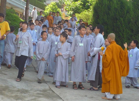 Hơn 600 học sinh tề tựu trong lễ khai giảng. Buổi học thiền đầu tiên. Không giấu nổi sự hồn nhiên. Cùng nhau xuống núi đi khất thực. Cười hồn nhiên trong giờ tiểu thực. Tập trung trở lại khu nhà ở sau giờ ăn trưa. Sư thầy nhẹ nhàng nhắc nhở các em nhỏ đi đúng hàng. Hai em nhỏ tranh thủ giờ nghỉ trưa xem lại bài vở. Các em cùng nhau học Phật pháp. Vốn là nơi tu hành của các bậc chư tăng, song để đáp ứng nhu cầu chúng sinh, Thiền viện Trúc Lâm Tây Thiên đã nhận giúp các "cậu ấm, cô chiêu" tập tu, sửa mình mà không thu bất cứ khoản lệ phí nào. Lớp học năm trước chỉ có 40-50 em nhỏ, do tiếng lành đồn xa, năm nay con số đã gấp hơn 10 lần. Các thầy phải chia làm nhiều khóa học để tiếp nhận các em. Khóa học đầu tiên dành cho các em từ 10 đến 14 tuổi, khai giảng vào ngày 13/6 và sẽ kết thúc sau 2 tuần. Thiền sư Thích Kiến Nguyệt, trụ trì Thiền viện Trúc Lâm Tây Thiên cho biết, do khuôn viên và số lượng thiền sư có hạn nên không thể nhận cùng lúc tất cả em nhỏ. Hiện 90 thầy, cô phải làm việc hết mình để quản lý, dạy dỗ 600 em nhỏ. Nói về lợi ích của việc tu tập, đặc biệt là ngồi thiền, thầy Nguyệt nhận xét: “Thiền là phương pháp tĩnh tâm khai trí. Khoa học đã chứng minh đứa trẻ ngồi thiền thông minh, kiên nhẫn hơn những đứa trẻ không ngồi thiền. Hiện nay, ở nhiều nước đã đưa thiền vào chương trình giáo dục. Các em tranh thủ đọc sách Phật trong giờ nghỉ. Ảnh: Hải Đăng. Ngoài việc học thiền, các sư thầy, sư cô sẽ chỉ dạy cho các em thói quen thức dậy từ 3h sáng, gập chăn màn sao cho vuông vức, ngay ngắn, sau đó nhẹ nhàng di chuyển về giảng đường để tọa thiền. Kết thúc giờ tọa thiền lúc 5h sáng, các em sẽ đến với bữa sáng gọi là tiểu thực. Lũ trẻ tay cầm bát, xếp thành hàng dài ngay ngắn đi về phía Trai đường để tự chọn khẩu phần ăn chay cho mình. 7h30 là bắt đầu giờ học đạo. Các em nhỏ được dạy kinh Phật để biết nhìn vạn vật bằng tình yêu thương, biết đúng, biết sai để sớm "phát tâm tỉnh giác, xa lìa chỗ tối tăm". 11h trưa là đến giờ khất thực (ăn trưa). Trước khi ăn, lũ trẻ phải chắp tay cầu nguyện và cùng nghe thầy giảng về nguồn gốc hạt lúa, củ khoai, ý nghĩa của những bữa ăn chay... Buổi chiều những cậu ấm, cô chiêu vốn quen với nếp sống thị thành, quen với sự nuông chiều, ỉ lại vào cha mẹ, người thân, được dạy cách làm việc nhà như: nấu cơm bằng bếp củi, rửa bát, nhặt rau... Các em kết thúc một ngày bằng lễ sám hối tại chánh điện, tức là xem xét lại tất cả những hành động trong ngày để nhận biết đúng, sai và sửa mình. Có nhiều lý do để các bậc phụ huynh đưa con em đến tập tu. Người thì muốn con tách khỏi cuộc sống thường nhật để cai games, người muốn con được học Phật pháp để chúng hiểu rõ hơn về ý nghĩa cuộc sống, trân trọng những gì đang có, để chúng biết được nguồn gốc của hạt lúa, củ khoai, biết trân trọng thành quả lao động của người khác. Và cũng có những ông bố bà mẹ đưa con lên chỉ để con biết thế nào là nhặt rau, quét nhà, nấu cơm… Chia sẻ cảm giác về ngày đầu tập tu, cô bé Phạm Phương Thảo, 14 tuổi, thật thà: “Cháu chẳng muốn lên đây, ở đây chán lắm, chẳng qua là bố mẹ ép. Cháu nghiện Audition nặng, chỉ cần hai chai nước, chẳng cần ăn gì, cháu có thể ngồi cả ngày. Giờ này bọn bạn cháu chắc đang ngồi ở quán net đầu đường Tô Hiệu (Cầu Giấy, Hà Nội)". Khác với sự bạo dạn của Thảo, hai chị em Nguyễn Việt Hà (14 tuổi) và Nguyễn Việt Hương (6 tuổi) ở Đống Đa (Hà Nội) tỏ ra dè dặt khi tiếp xúc với người lạ. Hương nhỏ tuổi nhất tại khóa học lần này. Thấy bố mẹ đưa chị lên đây để có thời gian nghỉ ngơi sau một năm học vất vả, cô bé nhất định đòi lên cùng chị. Đôi mắt sưng húp, Hà nói: “Hết giờ sám hối chiều qua, em cháu bắt đầu khóc đòi mẹ. Các cô dỗ mãi nó mới chịu nín. 11h đêm nó lại khóc, thế là cả phòng cháu khóc theo. Cháu nhớ nhà lắm. Cho cháu mượn điện thoại để gọi về cho mẹ được không?”. Được mượn điện thoại, cô bé vừa bấm số gọi cho mẹ vừa nước mắt lưng tròng. Cô chị ôm lấy cô em, thút thít nói chuyện với mẹ… Một em trai cũng không cầm được nước mắt vì nhớ nhà. Ảnh: Hải Đăng. Phía ngoài bậc thang bước lên giảng đường, hai ni cô cũng ra sức dỗ dành cậu bé Bùi Công Huy (10 tuổi) ở Hà Giang đang đòi về. Huy vừa khóc vừa nói: “Cháu không quen ăn chay, nhạt lắm. Ở đây cháu còn phải tự gập quần áo, nấu cơm, rửa bát, đến giờ ăn còn phải tự bưng bát, xếp hàng xới cơm… Cháu không quen, cháu muốn về với mẹ”. Các em lớn thì tỏ ra cứng rắn và thích nghi nhanh hơn với nếp sống tại thiền viện. Khuôn mặt tuấn tú, đeo kính cận, cậu bé Phan Thành Hưng (16 tuổi) ở phường Bách Khoa, Hà Nội, nhẹ nhàng lật giở quyển kinh. “Đây là lần thứ hai em lên thiền viện. Năm ngoái vì quá nghiện Internet nên bố mẹ đưa em lên. Năm nay, nghỉ hè là em xin bố mẹ lên luôn. Bây giờ em đã quen với việc ăn chay, dậy sớm từ 3h sáng, tự xúc khẩu phần ăn cho mình, tự rửa bát, quét nhà. Các thầy, các cô chỉ bảo ân cần lắm”, Hưng chia sẻ. Bóng chiều buông xuống, anh Quách Ngọc Huy (Tây Hồ, Hà Nội) đang chuẩn bị chia tay hai cô con gái để về Hà Nội. "Tôi có 3 con gái và muốn cả ba cháu lên đây nhưng vì cháu út mới 4 tuổi nên đành phải ở nhà với mẹ. Thú thật lên đây tôi thấy không khí thật thanh bình. Nhìn thấy con tự rửa bát, quét nhà mà tôi mừng quá. Ở nhà chúng có biết làm gì đâu. Tôi mong nhà chùa mở thêm nhiều khóa học như thế này để các em có được một học kỳ 3 thật hữu ích", anh Huy nói. 18h30 chiều, mặt trời đỏ lự phía sau mái chùa cong cong. Hàng thông reo vi vu. Phía nhà dân dưới chân núi, mấy cột khói bếp mịt mùng hòa vào khói lam chiều. Trên giảng đường ở thiền viện, đám trẻ nghiêm trang chắp tay trước tượng Phật và cầu nguyện theo các thầy để chúng sinh “xa rời đường dữ”, được ấm no, hạnh phúc.
