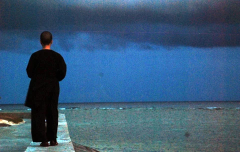 Một Sư cô đi dạo bên bờ biển khi cơn mưa sắp đổ lên đảo Sinh Tồn.