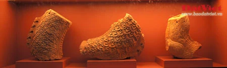 Những hiện vật này là ngói úp nóc có gắn lá đề trang trí rồng, phượng và tượng đầu rồng, đầu phượng... được dùng để gắn trên mái cung điện nhà Lý. Ở chính giữa mái cung điện là hình tượng lá đề lớn - biểu tượng của Phật giáo với đôi phượng chầu ở hai bên. Viên ngói gắn tượng đầu chim phượng này được dùng để trang trí đầu nóc mái cung điện. Theo tín ngưỡng dân gian, chim phượng một trong tứ linh (long, li, quy, phượng) và cũng là loài chim đẹp nhất trong số 360 loài chim. Đầu rồng thời Lý thống nhất ở kết cấu tạo hình: đầu nhỏ với miệng mở vờn một viên ngọc hay tinh tú đang xoay, răng nanh kéo dài xoắn với môi trên thành đường sống của chiếc mào có đường viền loăn xoăn như ngọn lửa đang bốc cao, phía trên mắt có những hoạ tiết hai đầu cuộn lại cùng chiều như số 3 ngửa và ngược chiều như hình chữ S, quanh mép có những lông măng và từ đó có một mảng kéo dài ra bốc lên lượn sóng làm bờm tóc. Hiện vật ở trên cũng là một viên ngói trang trí nóc mái. Ở hai bên của hình tượng lá đề lớn (nằm chính giữa nóc mái cung điện) là hai hàng ngói gắn lá đề lệch có trang trí rồng hoặc phượng. Tuy kích thước nhỏ nhưng những viên ngói này cũng được chạm khắc rất tỉ mỉ. Trong ảnh là ngói gắn lá đề lệch trang trí hình rồng. Còn đây là ngói gắn lá đề lệch trang trí hình chim phượng. Ngói ống lợp diềm mái gắn lá đề trang trí rồng (hoặc phượng) là loại ngói độc đáo nhất trong khu vực châu Á, mang bản sắc riêng của nghệ thuật kiến trúc cổ Việt Nam. Các di tích kinh đô cổ của các nước trong khu vực không có loại ngói ống cầu kỳ như thế này mà chỉ lợp ngói ống có đầu trang trí linh thú hay hoa sen, hoa cúc. Để thực hiện một lá đề gắn phượng (như trong ảnh), 40 nghệ nhân thời Lý phải thay phiên nhau chạm khắc trong hai ngày. Đến phiên của mình, mỗi nghệ nhân chỉ được phép thực hiện công việc trong khoảng 10 phút để đảm bảo sự tập trung cao độ nhất cho tác phẩm... Những hiện vật này là ngói úp nóc tạo hình cổ rồng. Không chỉ tượng trưng cho quyền lực hoàng gia, rồng thời Lý còn tượng trưng cho nguồn nước, nguồn sống của các cư dân trồng lúa. Những mảnh vỡ này thuộc về các hình tượng trang trí bên thành bậc cung điện, gồm bàn chân linh vật sấu thần và một đoạn thân rồng. Đầu máng nước tạo hình đầu sư tử (trên) và một mảnh ngói úp nóc gắn tượng chim uyên ương tuyệt đẹp, minh chứng khác cho trình độ thẩm mỹ rất cao của người thời Lý. Gạch vuông trang trí hoa sen (trên) và gạch vuông trang trí hoa cúc dây (dưới) là loại gạch có độ dày từ 8-15cm, dùng để lát nền cung điện. Hoa văn trang trí trên gạch cũng thế hiện ảnh hưởng sâu đậm của Phật giáo. Những viên gạch này ghi niên hiệu "Long Thụy thái bình tứ niên tạo", nghĩa là gạch được làm vào triều vua Lý thứ 3 - tức Lý Thánh Tông (1054 - 1072), niên hiệu Long Thuỵ Thái Bình thứ 4.