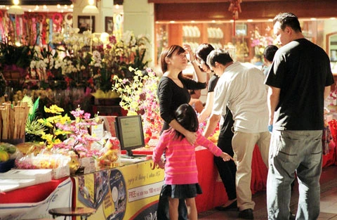 Người mua hàng bên ngoài gian bán hoa bằng nhựa và vải.