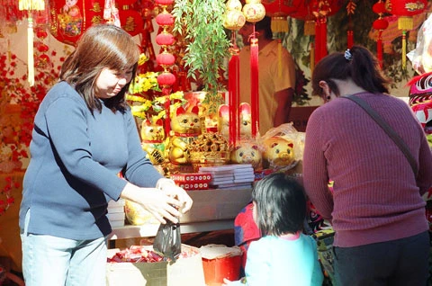 Cô chủ cửa hàng bán đèn lồng, phong bao lì xì, pháo đon đả với khách.