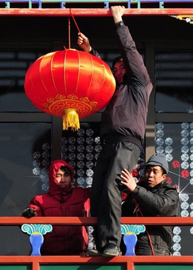 Một nhân công đang được hai đồng nghiệp giữ để treo đèn lồng đón Tết tại Bắc Kinh, ngày 21/1.