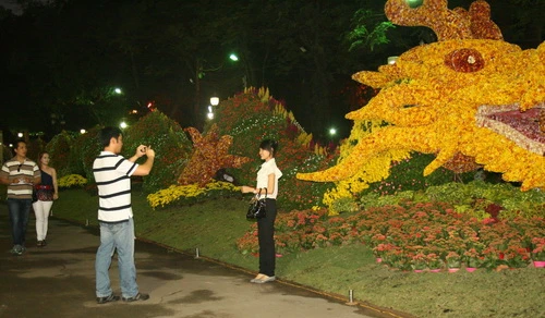 Du khách chụp ảnh lưu niệm bên con rồng kết từ hoa tại Hội hoa xuân ở công viên Tao Đàn, TP.HCM - Ảnh: Tường Vy