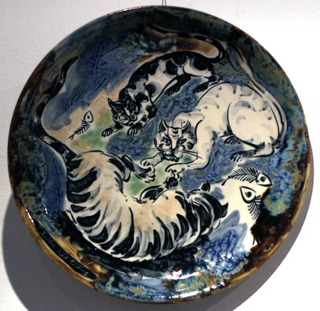 Hai chú mèo trong nét vẽ cách điệu quấn quít bên nhau trong tác phẩm "Tâm giao", thực hiện trên chất liệu gốm trắng men màu của nghệ sĩ Đặng Toàn Hưng. Hình tượng mèo thể hiện qua những hình khối vuông trong tác phẩm làm bằng sành trắng có tên Mèo cá của nghệ sĩ Nguyễn Mạnh Thẩm. Một chú mèo uốn mình trong tác phẩm sơn mài trên đĩa của tác giả Nguyễn Thanh Giang. Hai chú mèo tạo nên họa tiết cân xứng trên - dưới trong tác phẩm làm bằng sành nâu có tên Song mão của tác giả Nguyễn Mạnh Thẩm. Giấc mơ của một chú mèo được thể hiện trong tác phẩm của nghệ sĩ Nguyễn Duy Nghiêm. Chú mèo cuộn tròn tạo nên vẻ sinh động và ấm cúng trong bức tranh sơn mài có tên Đêm trăng của nghệ sĩ Đặng Vũ Đạt. Phải nhìn kỹ mới nhận ra có đến ba chú mèo trong tác phẩm "Đời thường" của tác giả Đặng Toàn Hưng. Những chú mèo trong tác phẩm Đĩa tam hợp của nghệ sĩ Lê Quang Chiến.