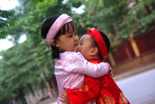 Các bé mặc áo dài, quấn khăn đống đi chúc Tết rất dễ thương. Mặc dù chưa hiểu hết được ý nghĩa của việc mặc áo dài truyền thống và những câu chúc tết nhưng các bé tỏ ra rất hào hứng trong trang phục mới. Đa dạng các kiểu áo dài cách tân dành cho các bé trong dịp Tết này. Tung tăng xuống phố. Và tạo dáng dễ thương Ngộ nghĩnh trẻ em áo dài, khăn đống chúc Tết