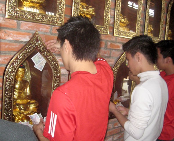 Cố gắng nhét từng đồng tiền lẻ vào khe hở các ô đặt tượng Quan Âm. Cố gắng nhét từng đồng tiền lẻ vào khe hở các ô đặt tượng Quan Âm.